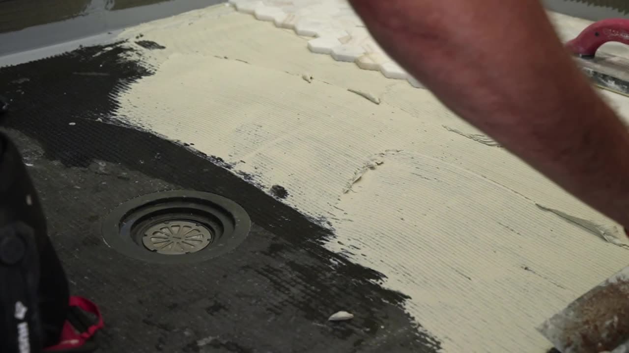 Harlan Custom Contracting installer setting mosaic tile over a waterproofed shower pan