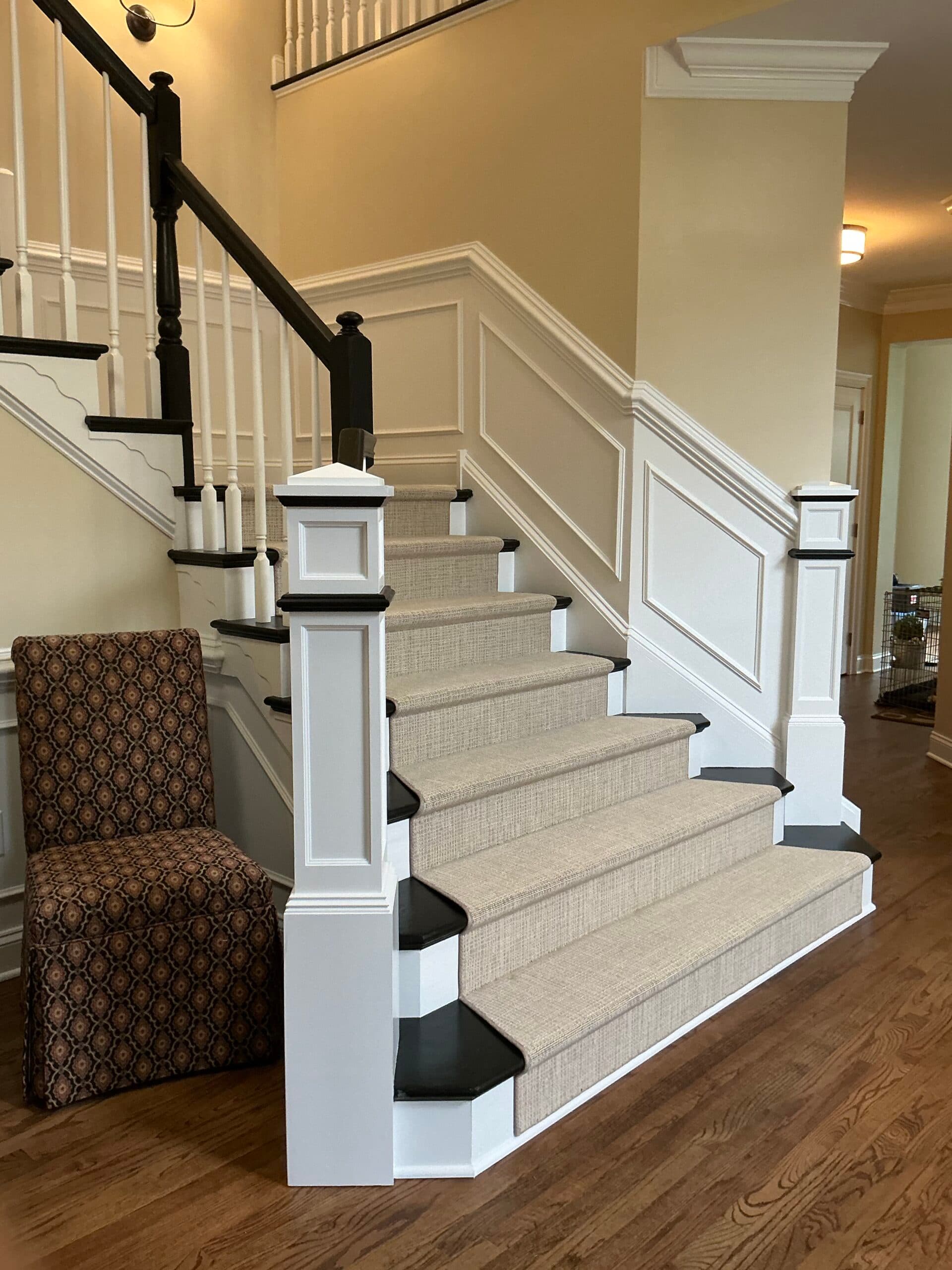Renovated staircase with custom wainscoting, newel posts, and refinished hardwood by Harlan Custom Contracting