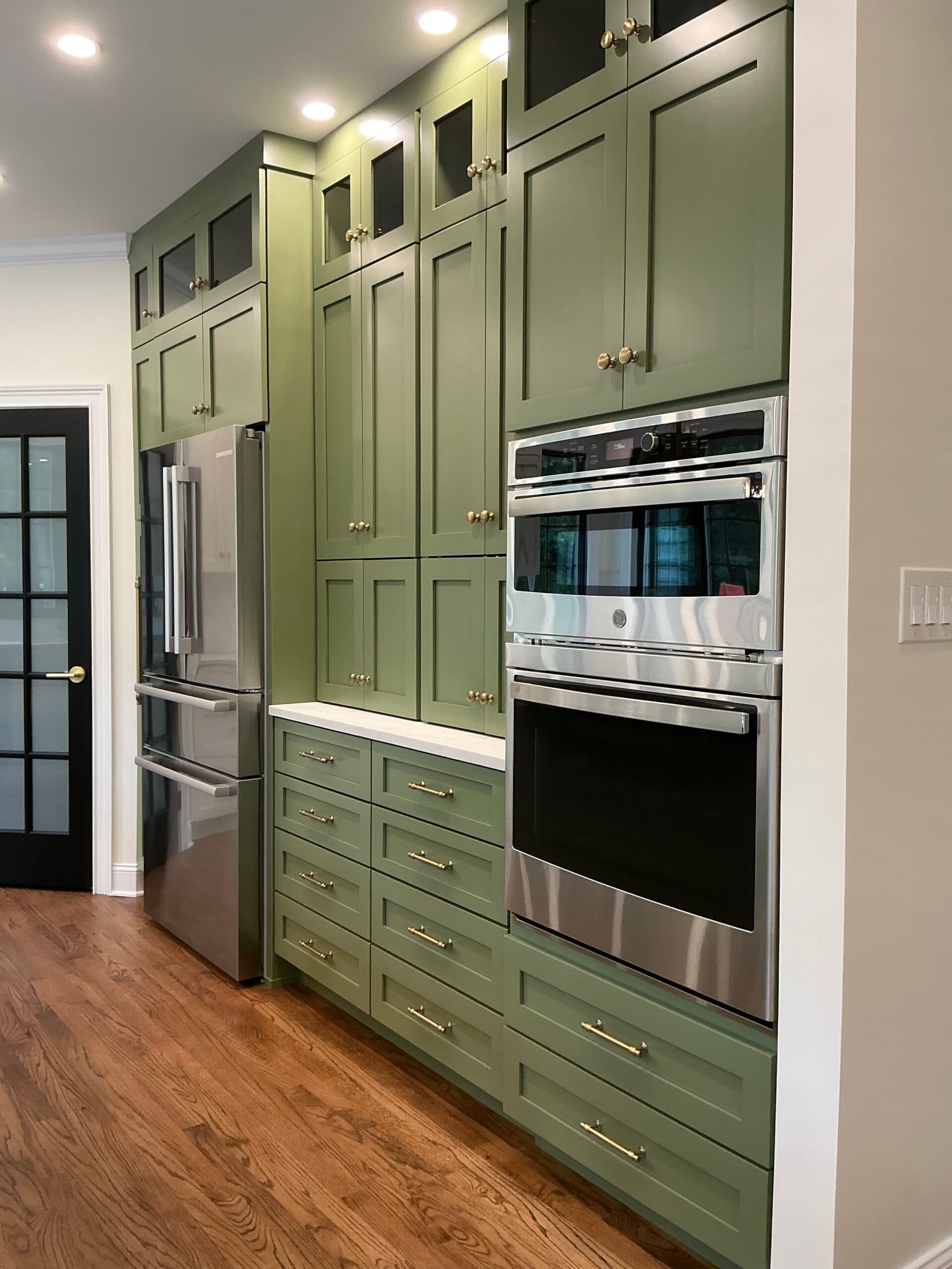 Floor-to-ceiling sage green cabinetry with integrated double wall oven — Harlan Custom Contracting project