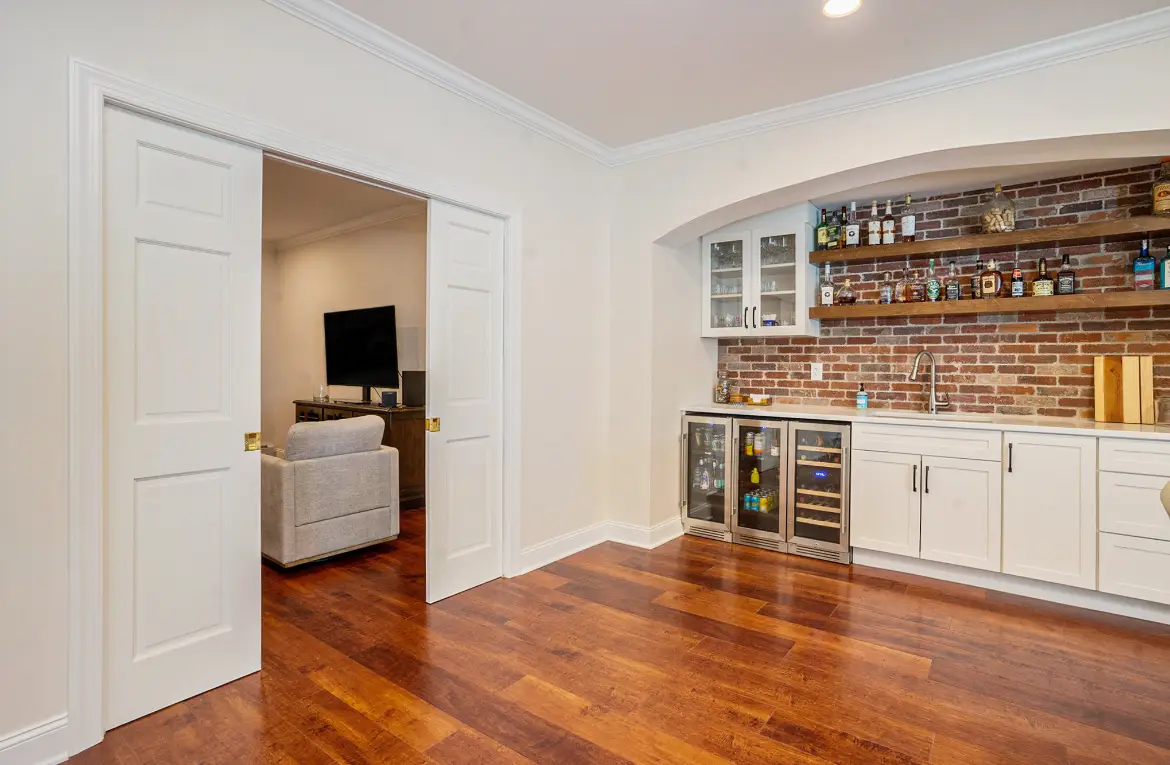 Basement wet bar with arched brick niche, floating shelves, and beverage centers — Harlan Custom Contracting project