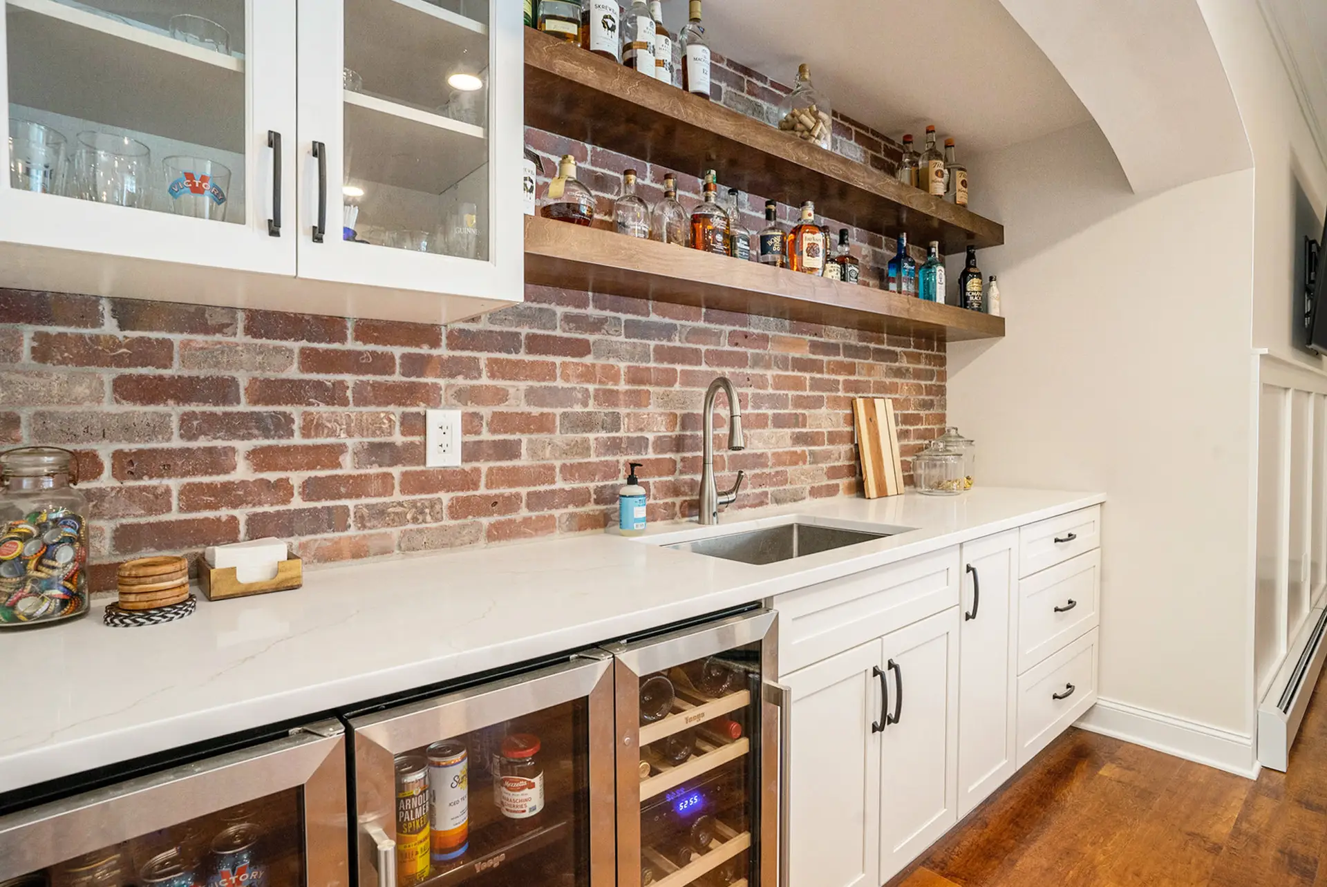 Home bar with exposed brick backsplash, floating wood shelves, and beverage centers — Harlan Custom Contracting project