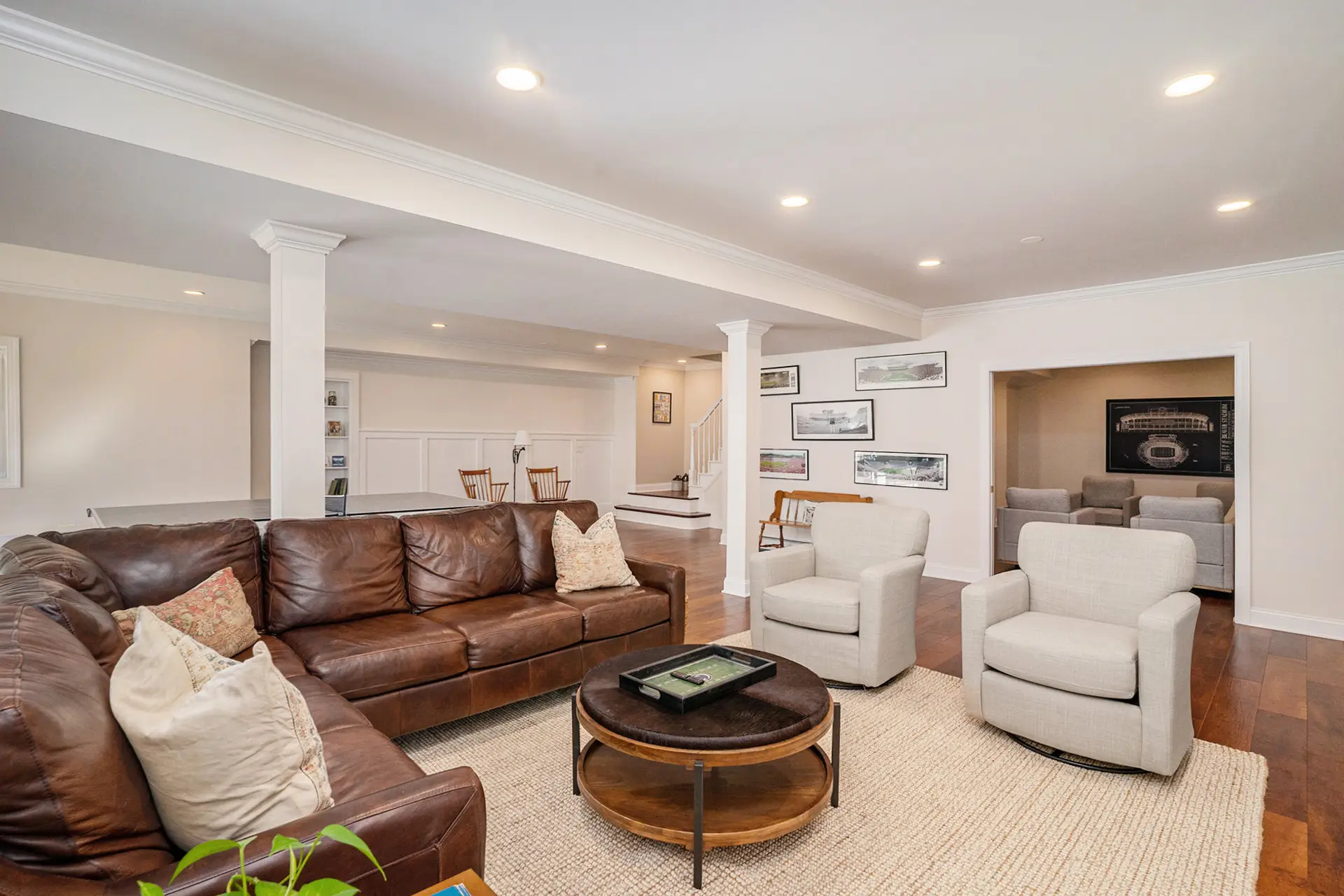 Open-plan finished basement with columns, gallery wall, and staircase — Harlan Custom Contracting project
