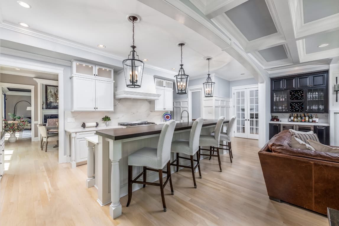 White kitchen with coffered ceiling, lantern pendants, and walnut-topped island — Harlan Custom Contracting project