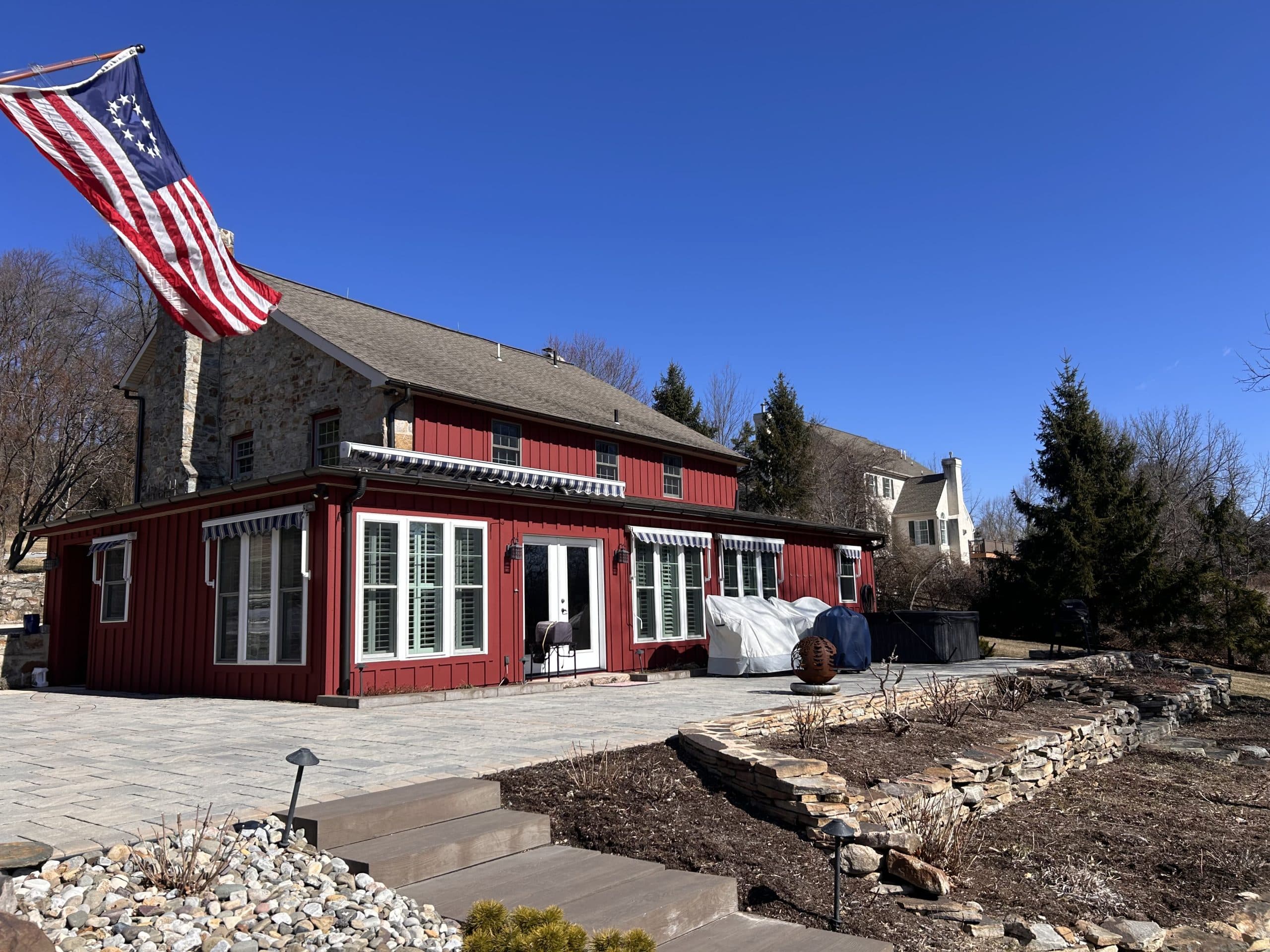 Renovated stone farmhouse with board-and-batten addition and paver patio managed end-to-end by Harlan Custom Contracting