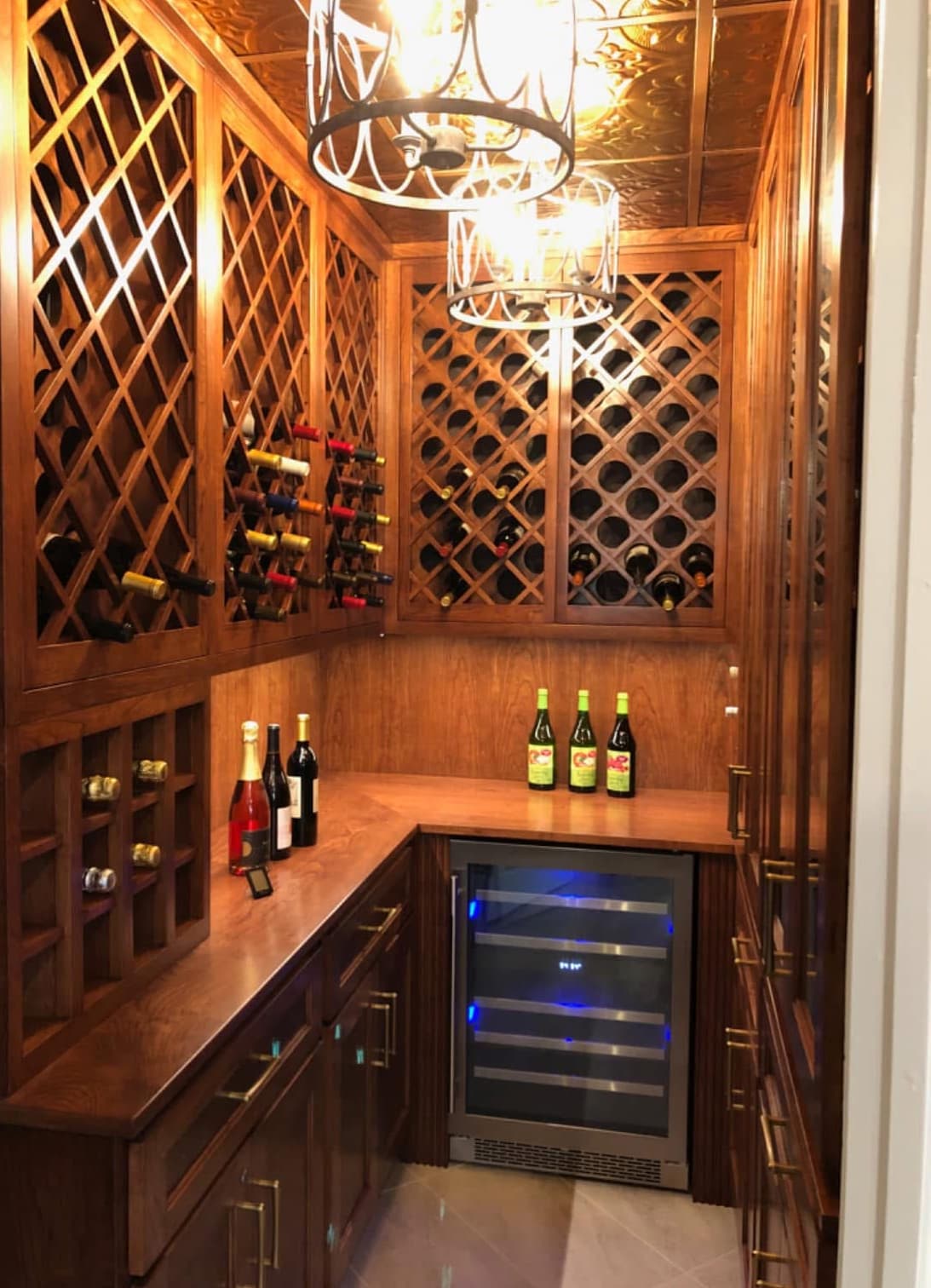 Custom wood wine cellar with lattice racking, counters, and beverage refrigerator — Harlan Custom Contracting project
