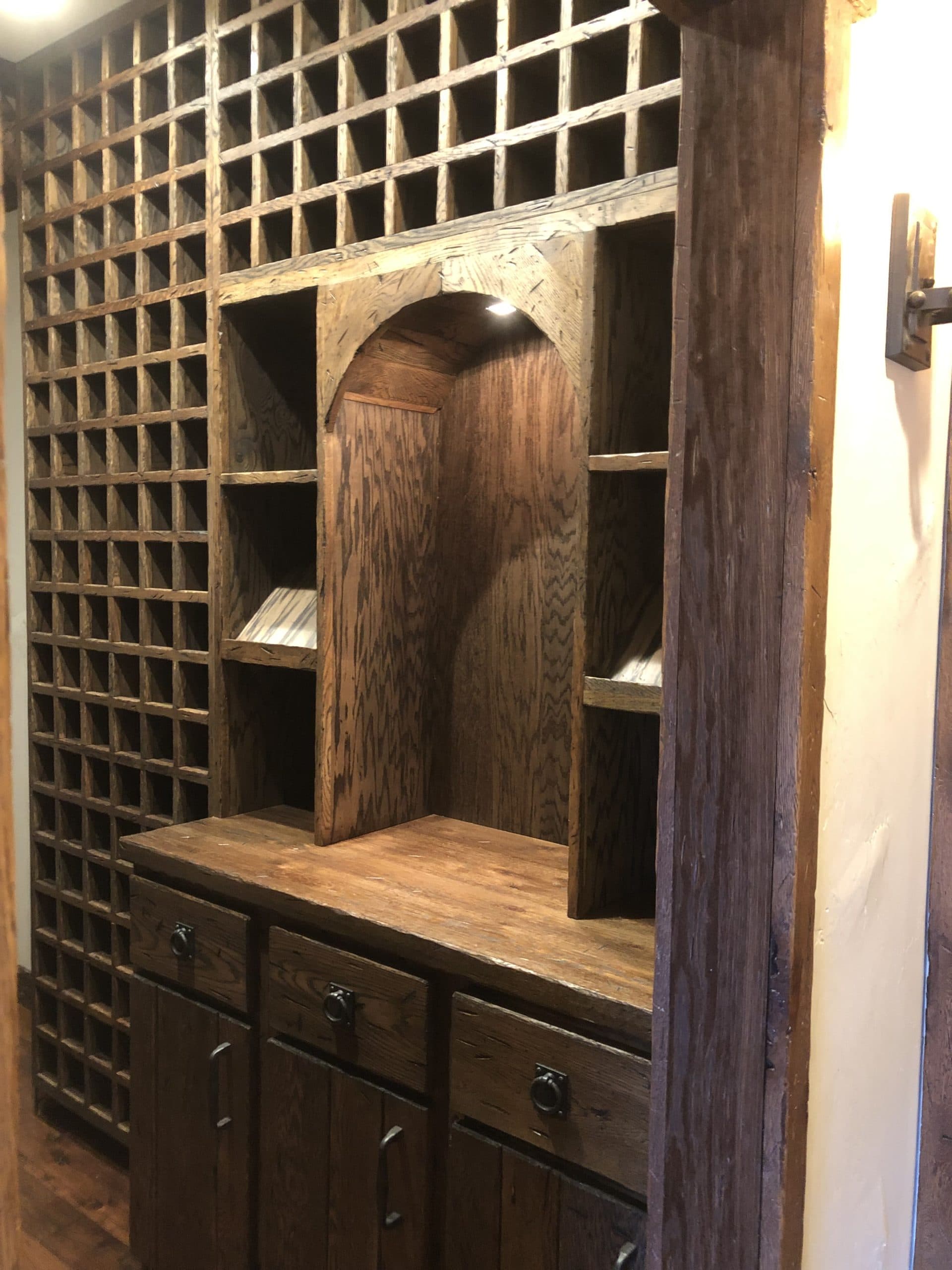 Floor-to-ceiling custom oak wine racking with arched display niche — Harlan Custom Contracting project