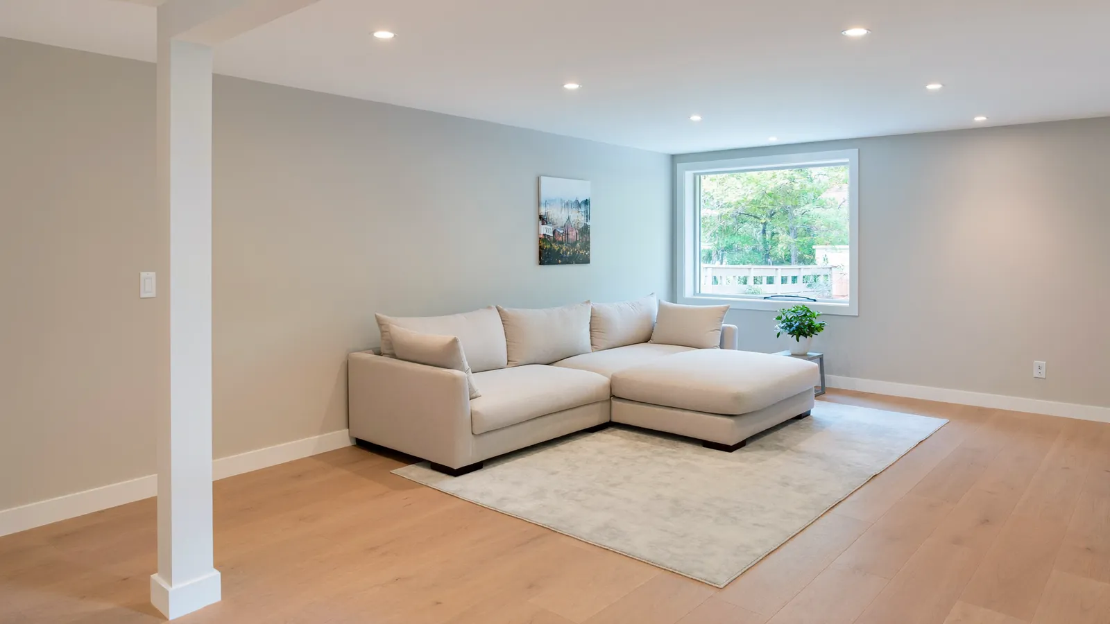 Finished basement family room with egress window and recessed lighting